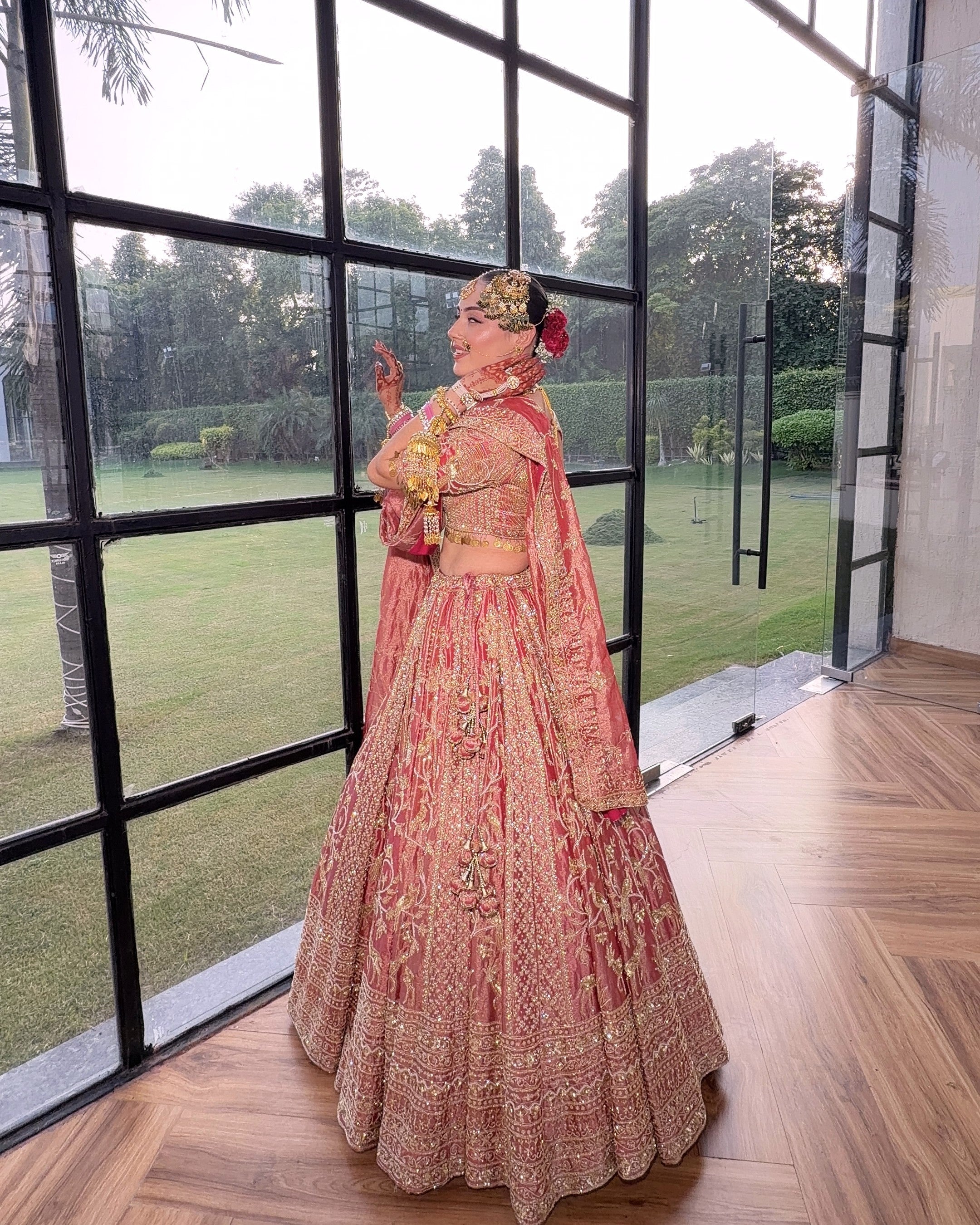 Gulrang pink tissue bridal lehenga, full length by a window, Amaltas Couture